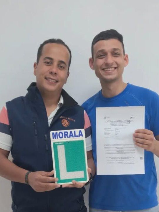 تلميذ ناجح يحمل لوحة L الخاصة بمورالا ونتيجة امتحانه، مع أستاذه